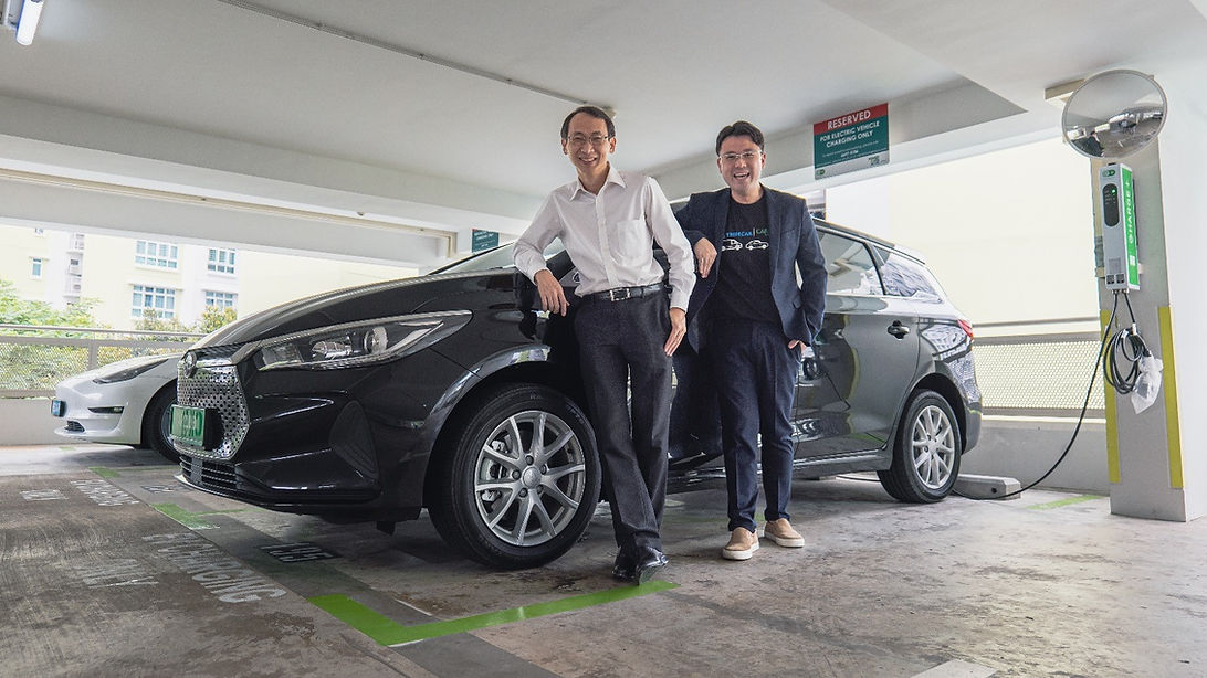 From L to R: Goh Chee Kiong, CEO of Charge+, and Adrian Lee, co-founder of Tribecar, in front of Tribecar vehicles at a Charge+ EV charging station